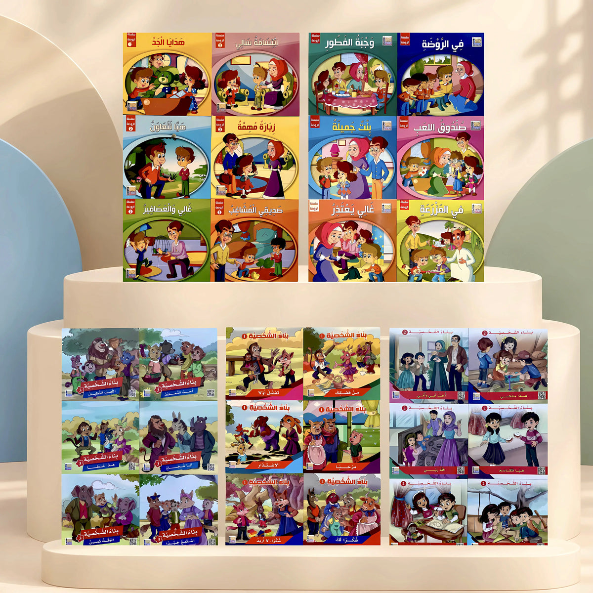 A set of colorful children's books arranged on white tiered display pedestals. The books feature Arabic titles and colorful cartoon-style covers and back covers showing children in various scenes.